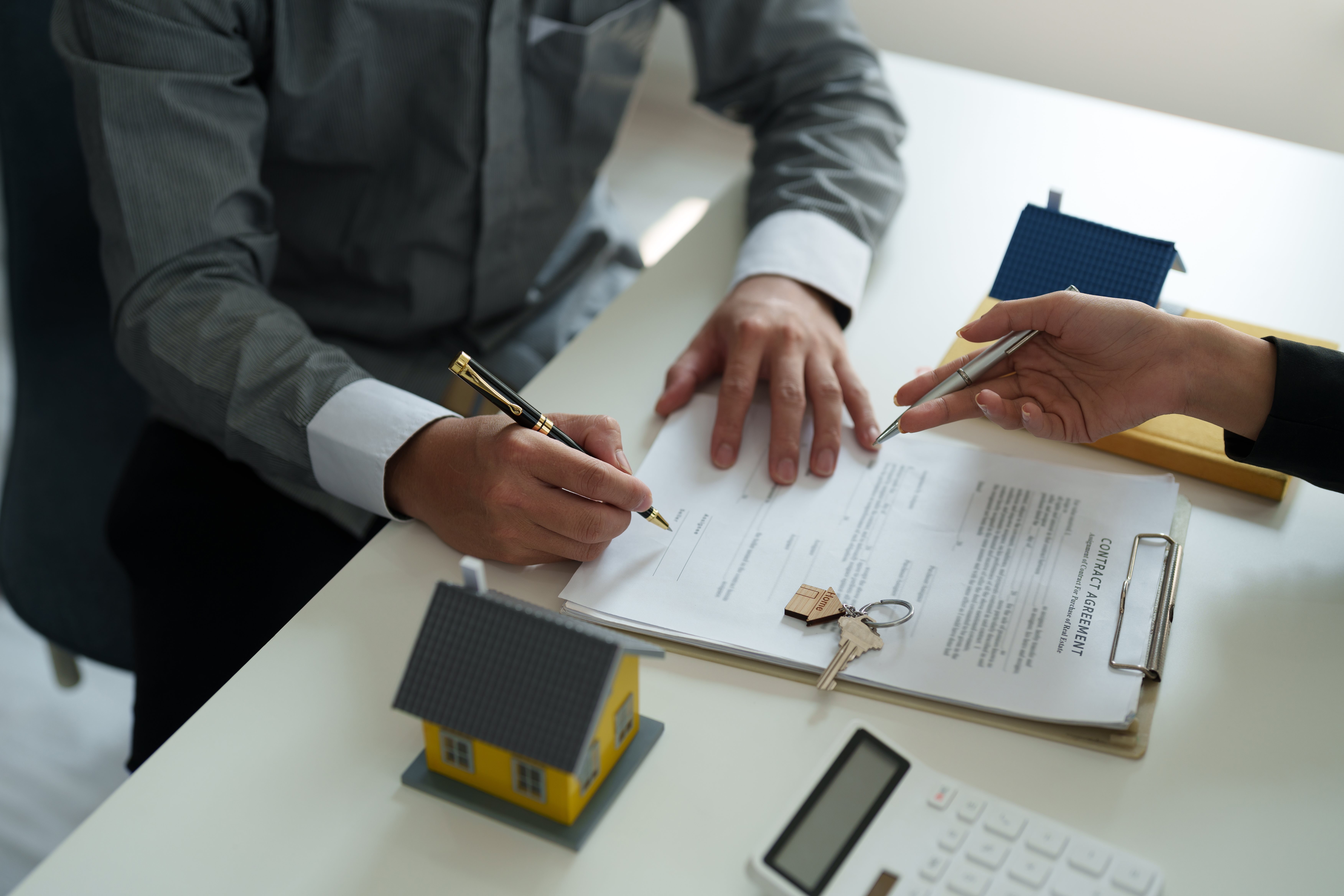 A man signs a contract agreement as a representative explains the details of the agreement.